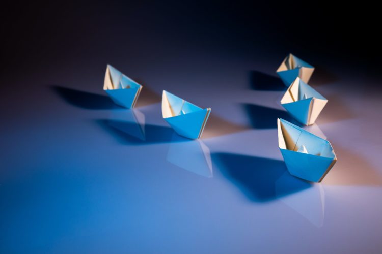 Five paper boats in a 'V' shape, with one leading the way.