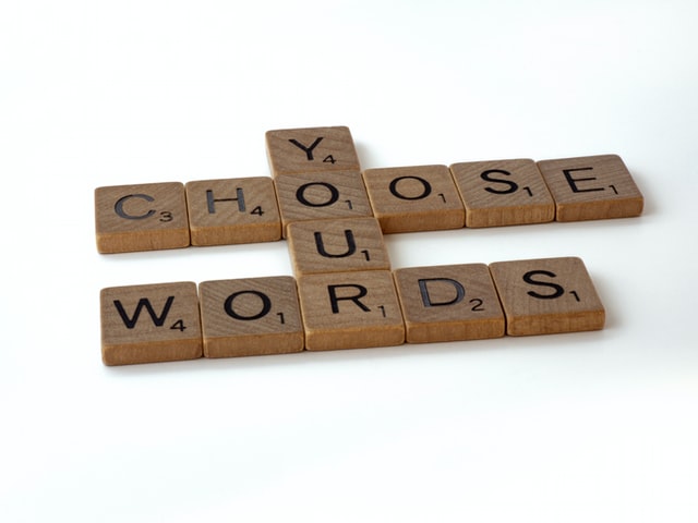 Wooden Scrabble letters spell out "choose your words".