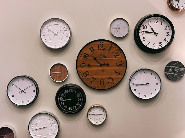 A group of analogue clocks of different sizes and colours.