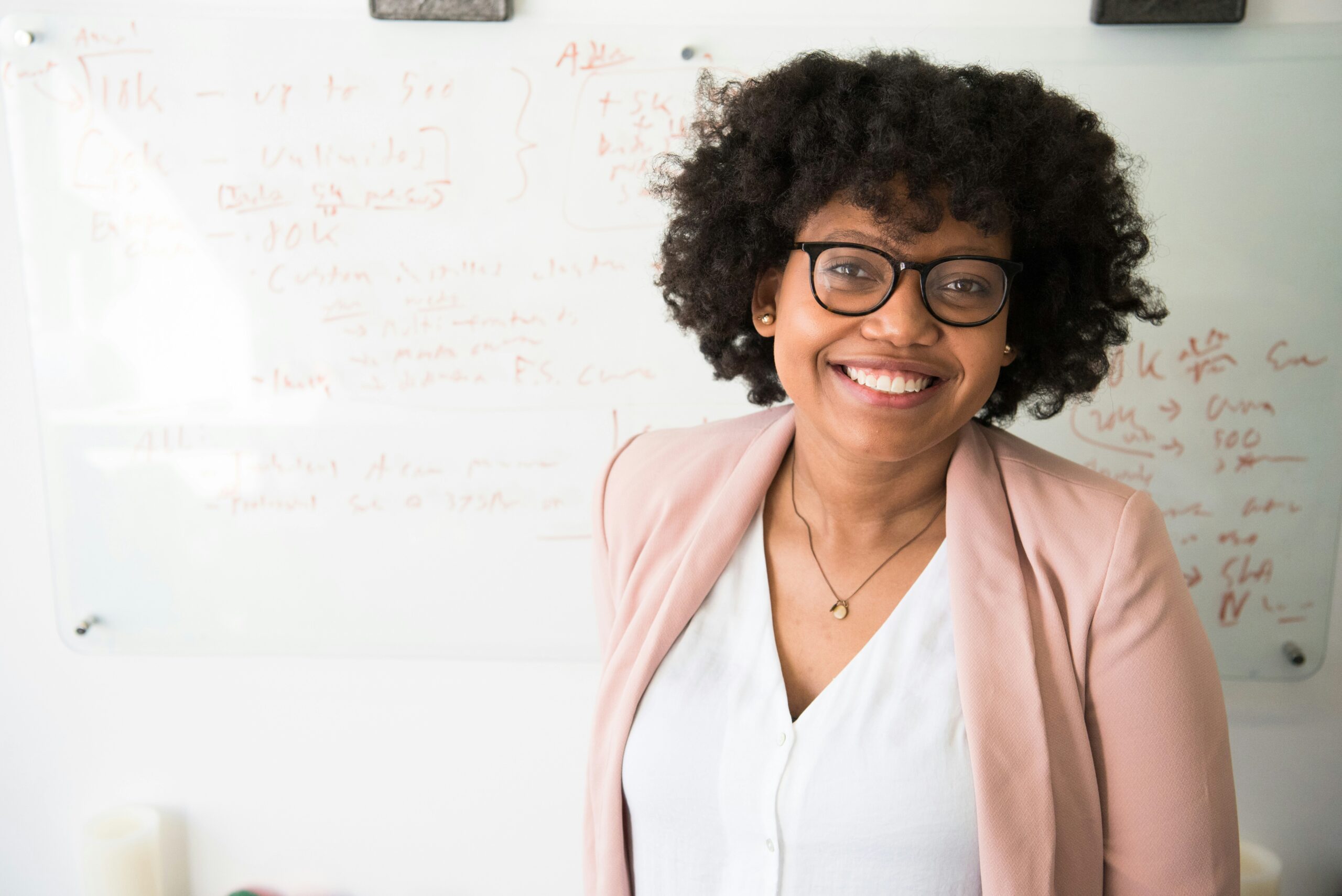 Woman standing in front of a whiteboard and smiling at the camera