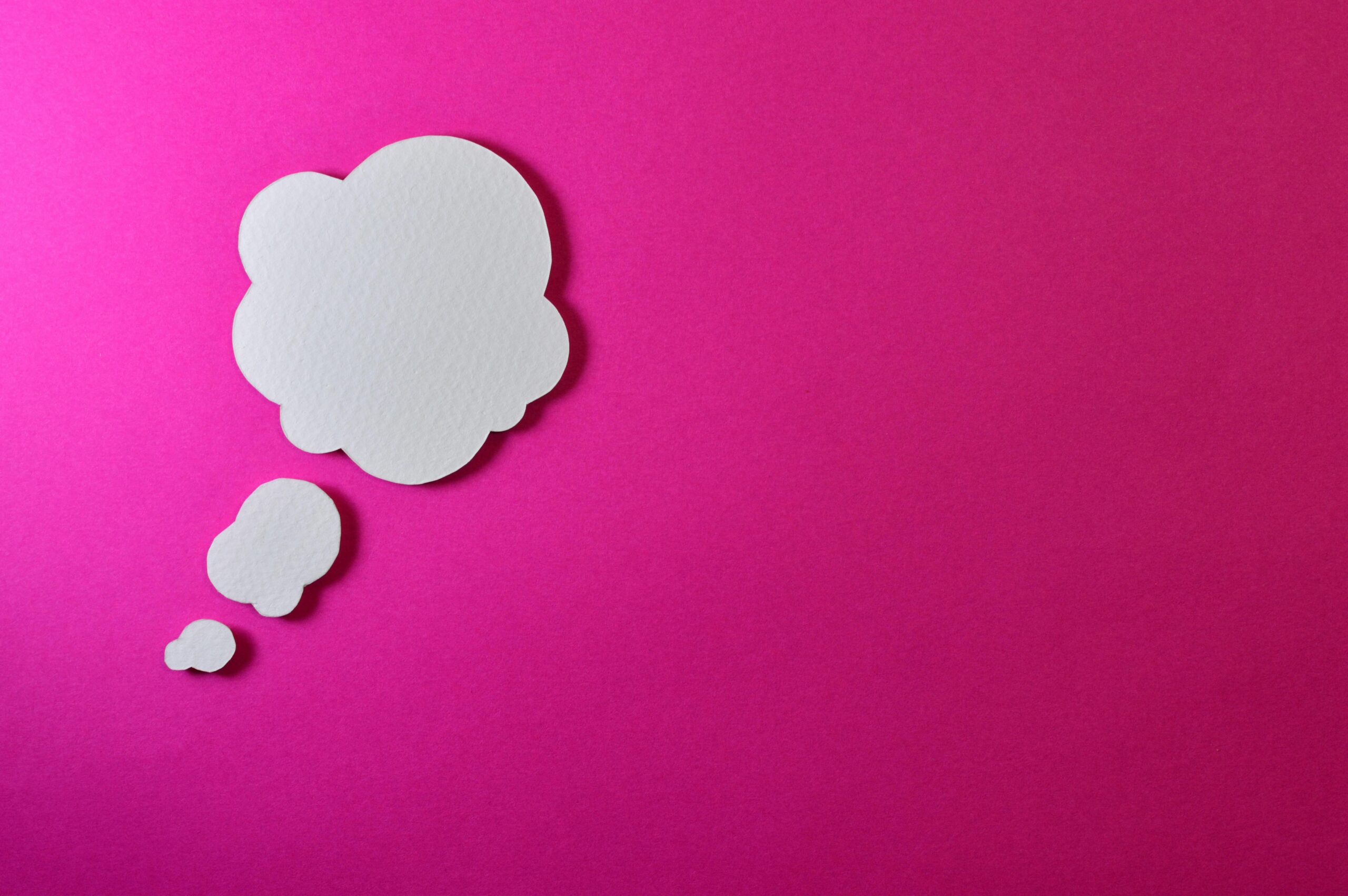 A white thought cloud floating over a pink background